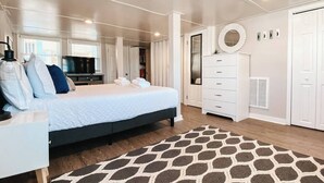 Een moderne slaapkamer met een bed, een kaptafel, een spiegel en een televisietoestel.