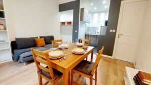 A compact living space with a dining area, a sofa, and a kitchenette. - Haussmannian apartment at the gateway to Paris (Aubervilliers)