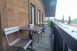 A wooden deck with metal tables and benches, overlooking a residential area with houses and trees. - Hotel Wetterstein (Seefeld in Tirol)