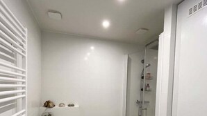 A compact bathroom with a toilet, a glass shower enclosure, and a small shelf with decorative items. - Prestigious Apartment - Faubourg Saint-Honoré (Paris)
