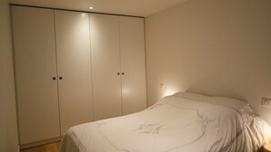 A bedroom with a large wardrobe, a bed with a floral bedspread, and a nightstand. - Prestigious Apartment - Faubourg Saint-Honoré (Paris)
