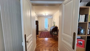 A hallway with a wooden floor, a piano, and a bookshelf. - In the Heart of Paris - Spacious 153 m² (Paris)