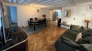 Amplia sala de estar con suelo de espiga, una mesa de comedor y un sofá.