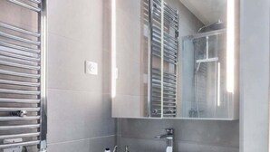 Un baño moderno con un espejo grande, un lavamanos blanco y un perchero para toallas.