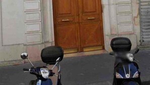 Un edificio con una puerta de madera doble grande, un pequeño balcón y un cartel con el número 30.