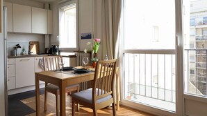 A dining area with a wooden table and chairs, a vase with flowers, and a view of the outside balcony. - Garden View Apartment near Canal Saint-Martin (Paris)