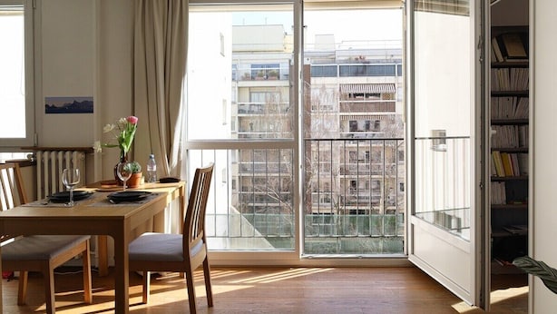A dining area with a table set for two, a chair, a potted plant, and a bookshelf. - Garden View Apartment near Canal Saint-Martin (Paris)