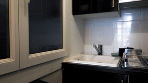 Une cuisine avec un évier blanc, des placards noirs et une fenêtre.