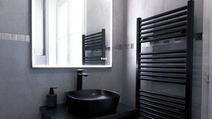 Une salle de bain moderne avec un lavabo noir, un miroir et un porte-serviettes noir.