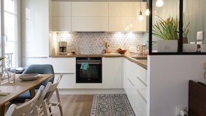 Een moderne keuken met witte kasten, een zwarte oven en een behangetje op de achterwand.