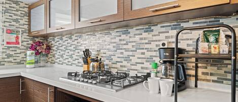 A modern kitchen with wooden cabinets, a gas stove, a coffee maker, and a tiled backsplash.