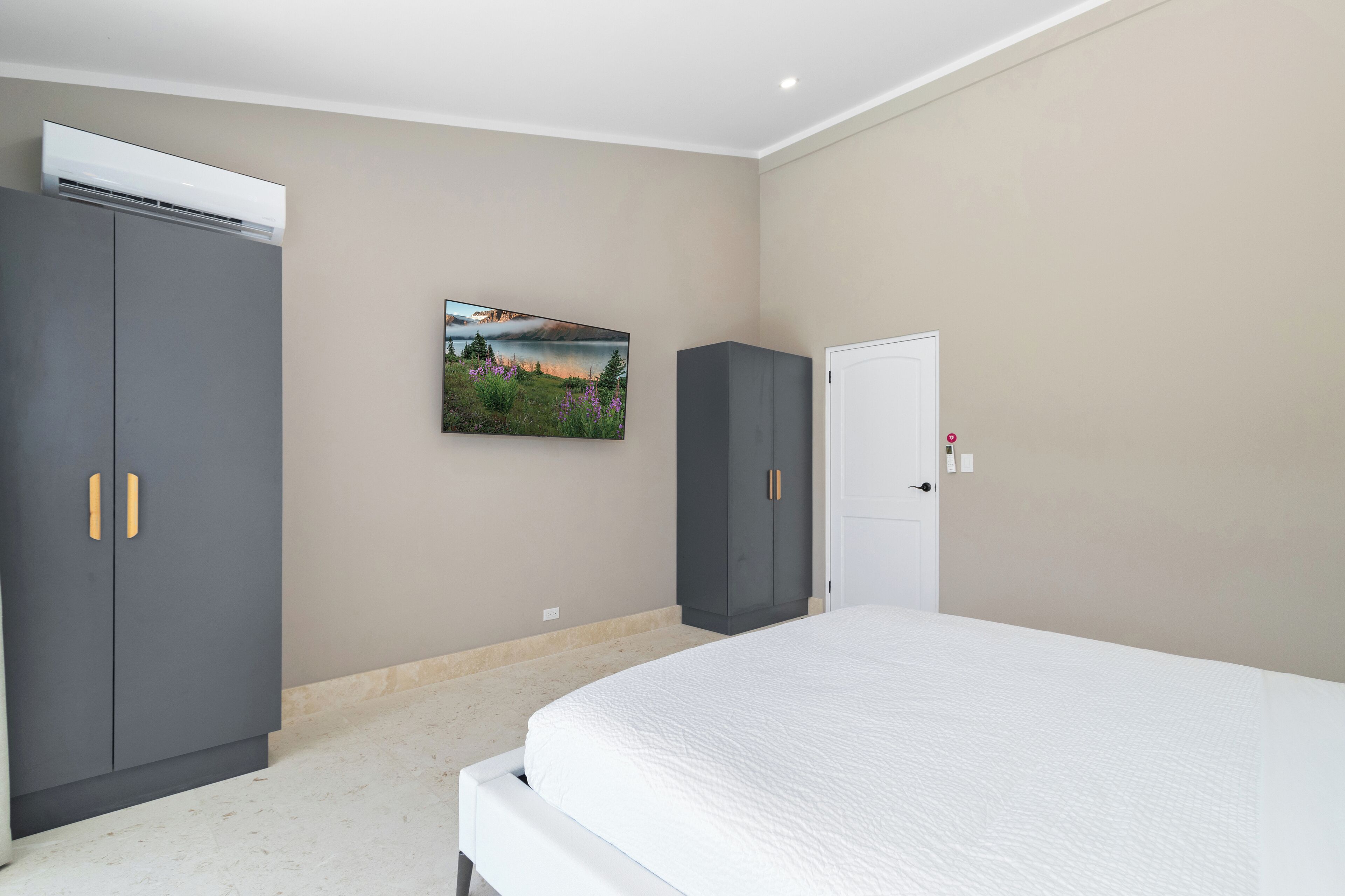 Een slaapkamer met een bed, twee kasten, een airconditioner en een landschapsschilderij aan de muur.