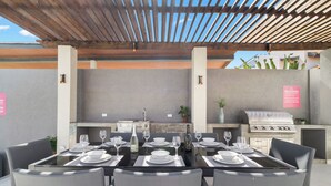 An outdoor dining area with a grill and a stone wall. - Salinja Cerca 23-b (Noord)