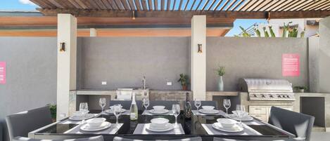 An outdoor dining area with a grill and a stone wall.