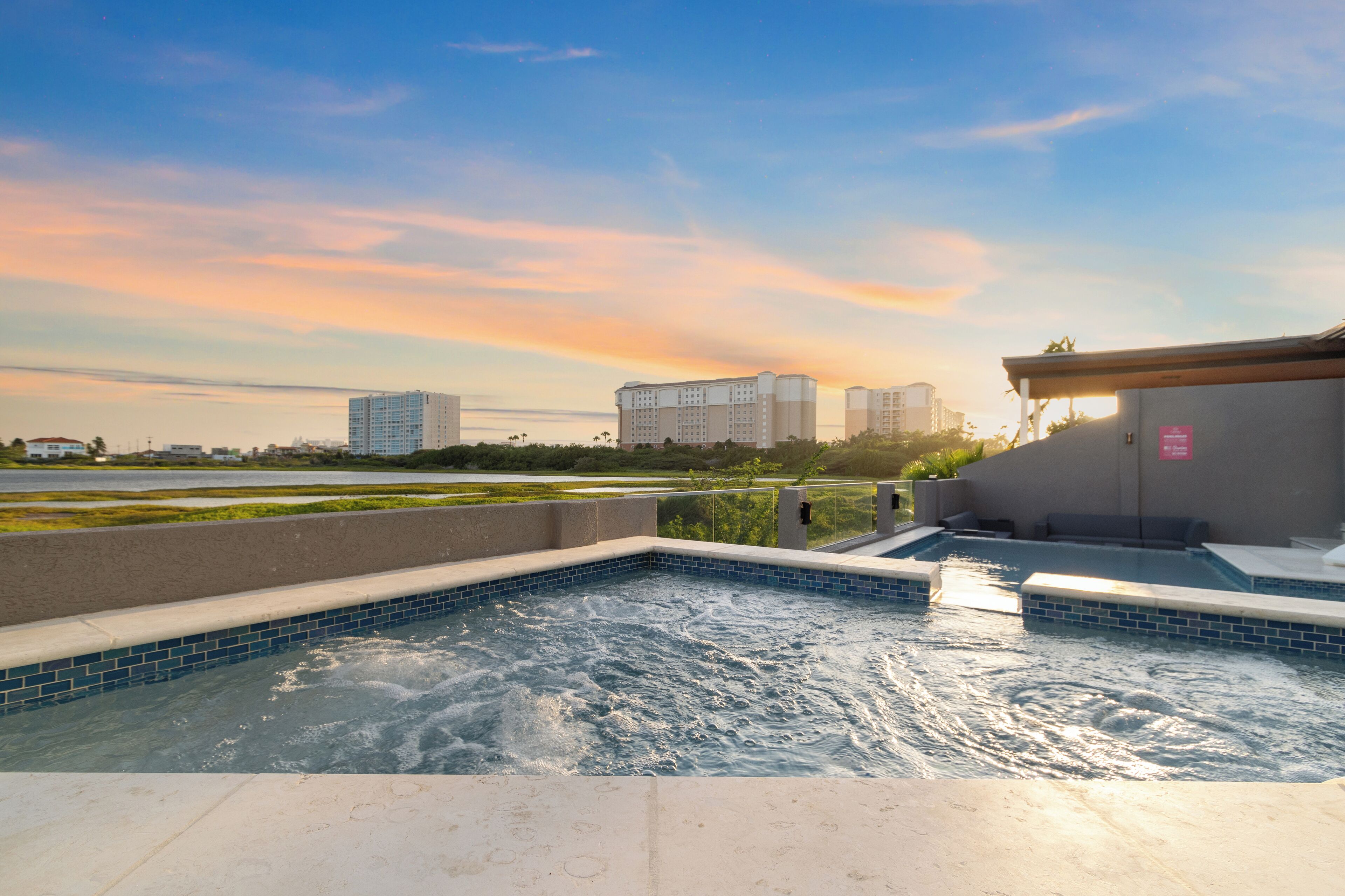 Una piscina en la azotea con vistas a rascacielos y un atardecer.