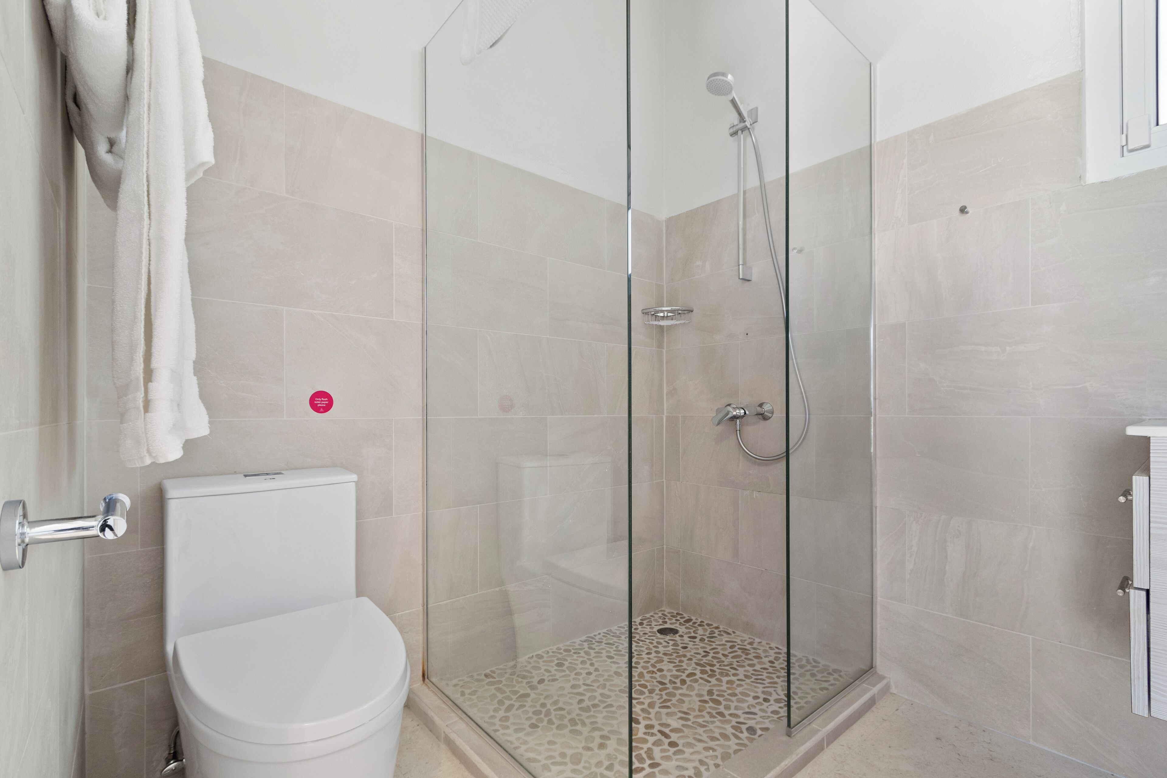 A modern bathroom with a glass-enclosed shower, a white toilet, and a tiled floor.