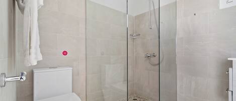 A modern bathroom with a glass-enclosed shower, a white toilet, and a tiled floor.