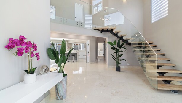 A spacious, modern interior with a glass staircase, potted plants, and a clean, polished floor. - Salinja Cerca 23-b (Noord)