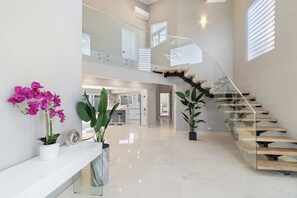 A spacious, modern interior with a glass staircase, potted plants, and a clean, polished floor. - Salinja Cerca 23-b (Noord)