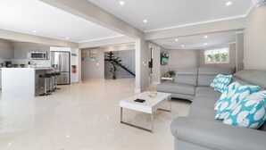 A spacious living area with a grey sofa, a white coffee table, and a kitchen area with modern appliances. - Salinja Cerca 23-b (Noord)