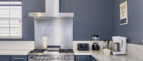 A modern kitchen with stainless steel appliances, a built-in oven, and a coffee maker.