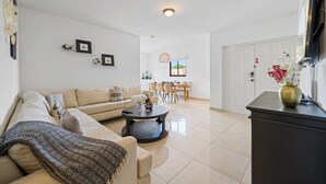 A modern living room with a sofa, coffee table, and a dining area in the background. - Felicidad 30 (Oranjestad)