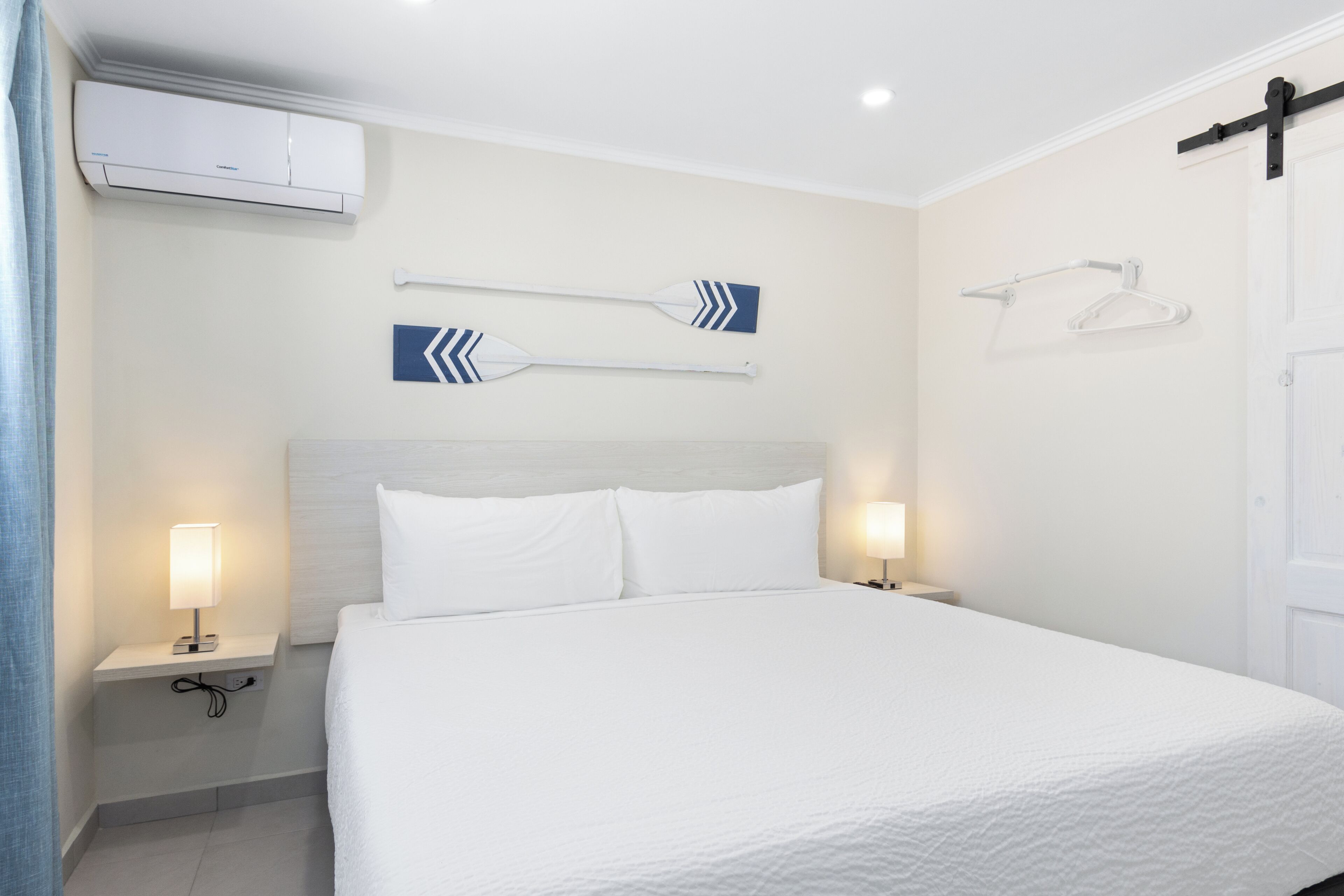 Ein Hotelzimmer mit einem Bett, zwei Nachttischlampen, einer Klimaanlage und Wandtuchhaltern.