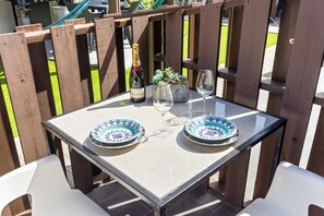 Enjoy a dining experience on this patio, surrounded by a fence, with a table set for two.