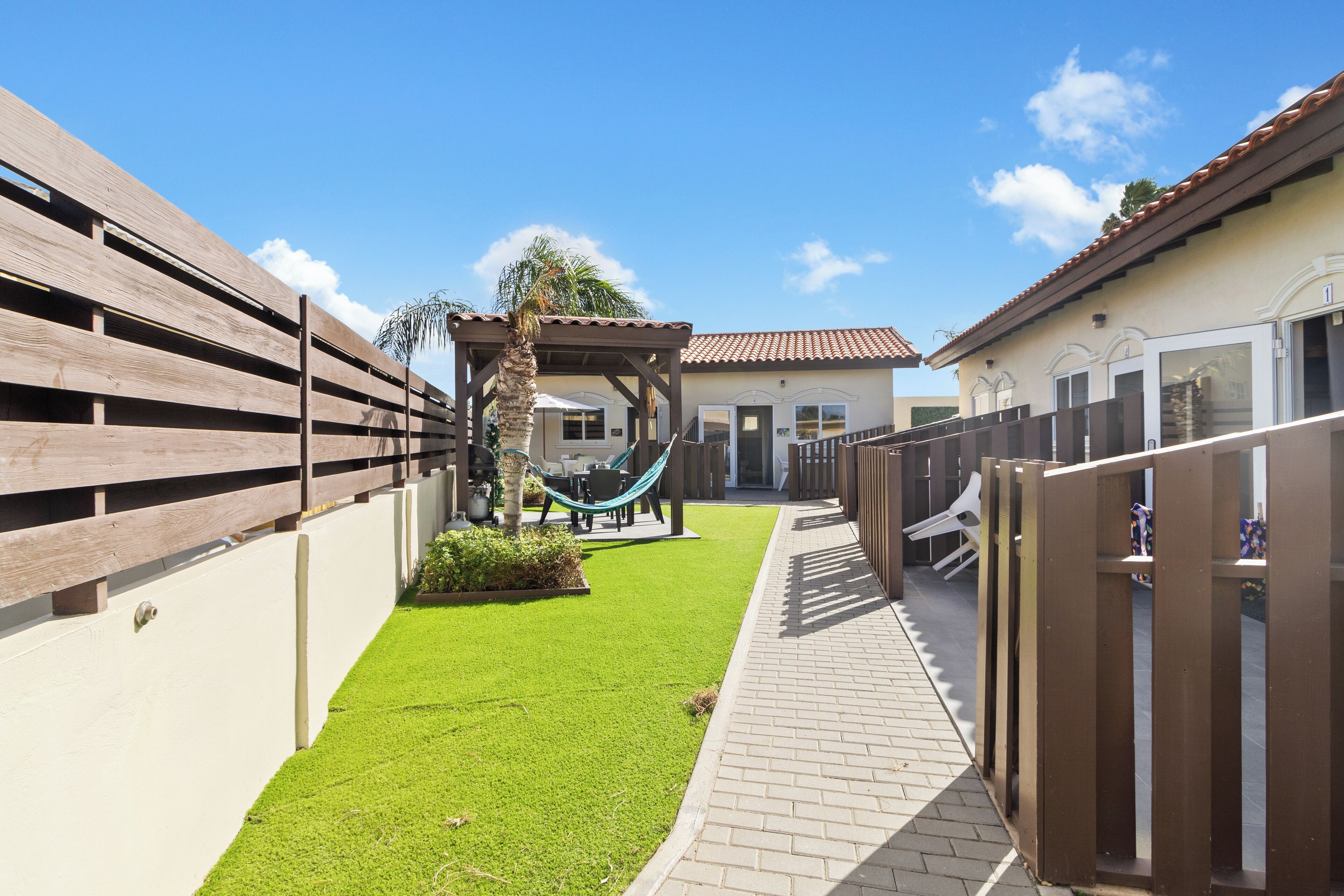 A courtyard with artificial grass, a hammock, and a brick pathway.