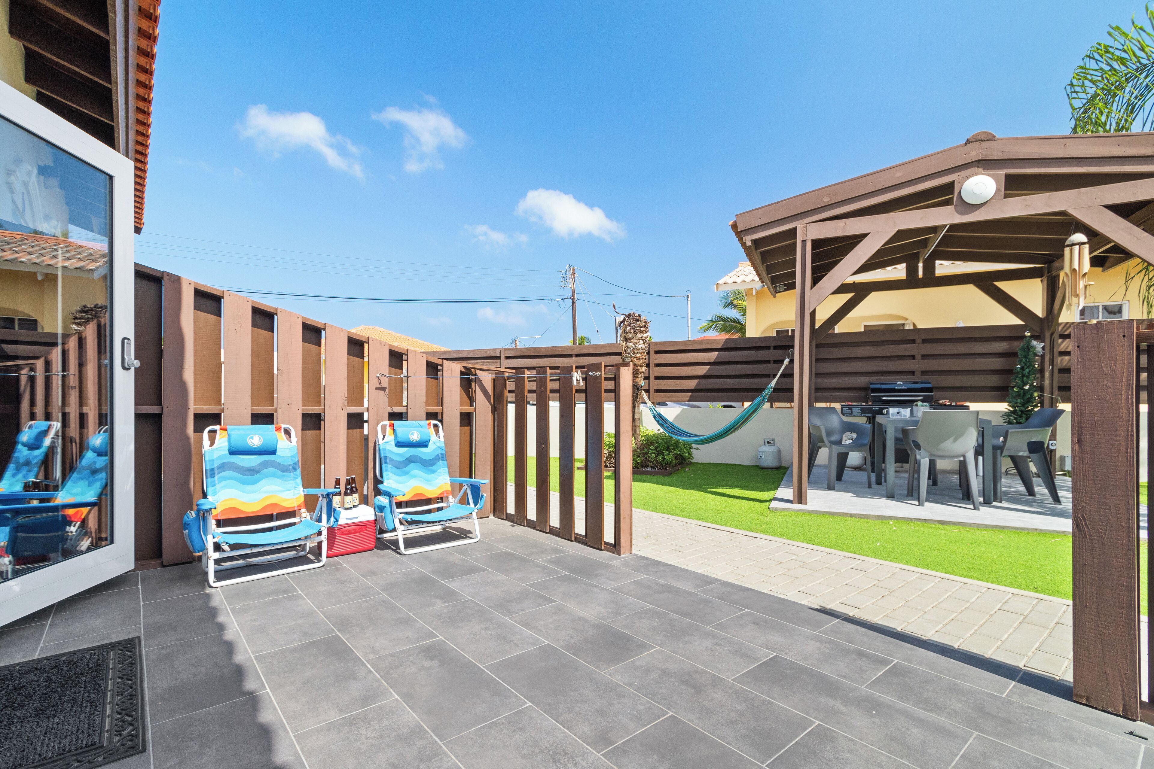 A patio area with two lounge chairs, a barbecue grill, and a hammock.