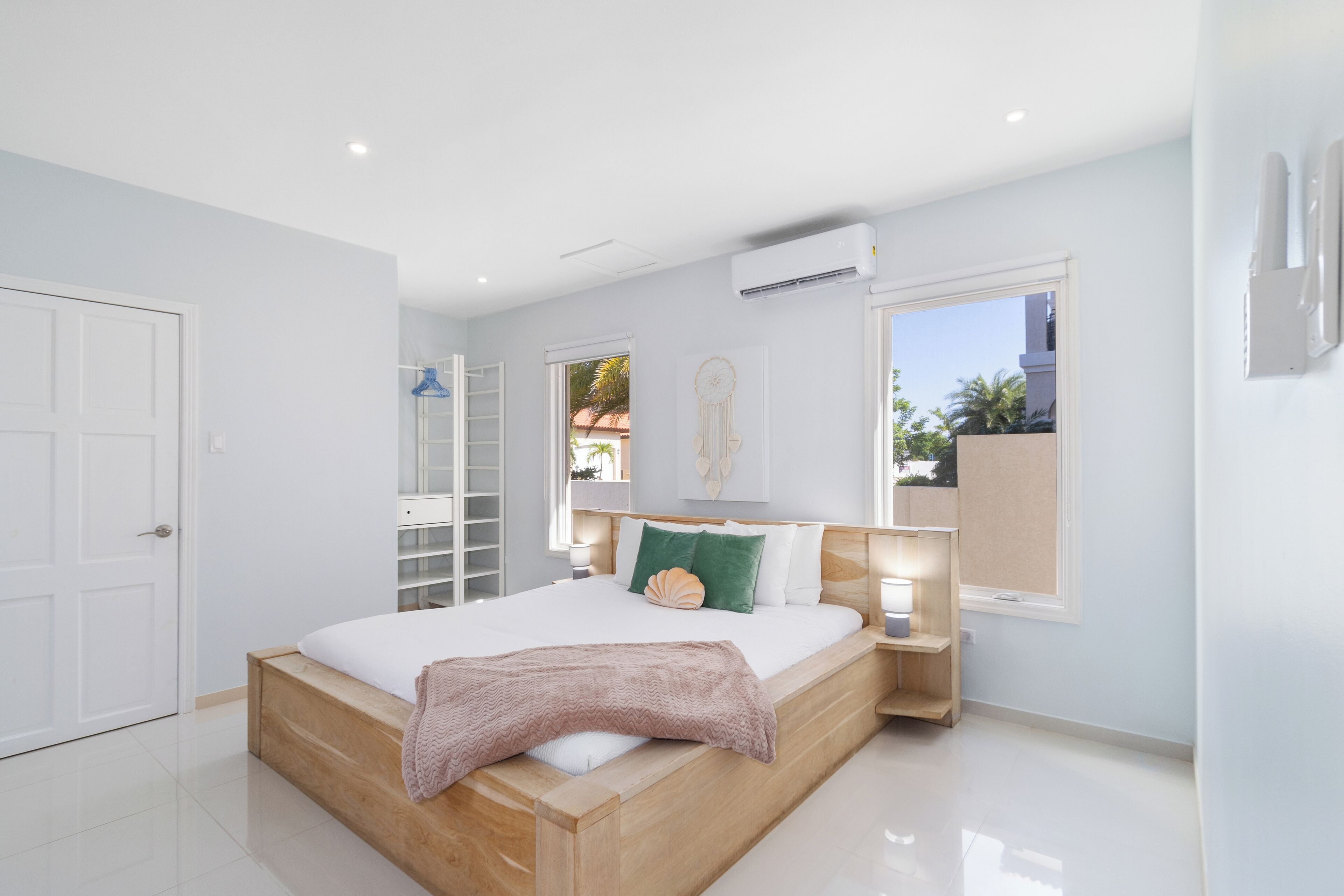 Un dormitorio moderno con una cama de madera, paredes blancas y un ventanal grande.