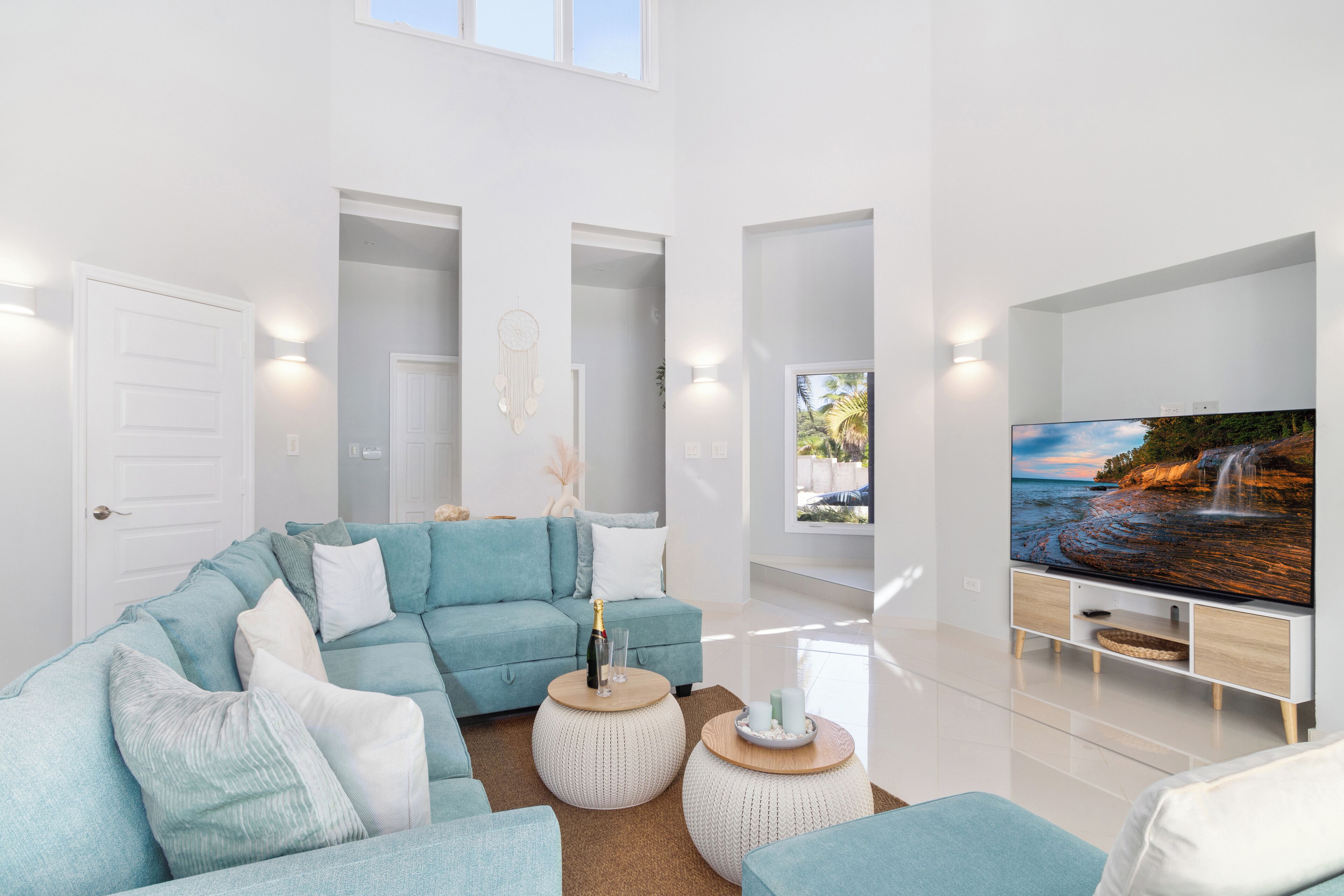 Una sala de estar moderna con un sofá modular, un televisor de pantalla plana y un amplio ventanal con vistas a una cascada.