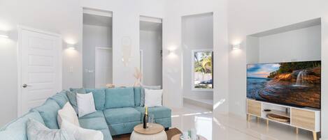 Una sala de estar moderna con un sofá modular, un televisor de pantalla plana y un amplio ventanal con vistas a una cascada.