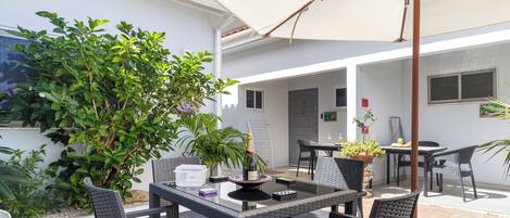 Un espace patio aménagé avec une table et des chaises, une plante en pot et une bouteille de champagne.