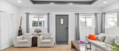 Una sala de estar moderna con dos sofás, una mesa de centro y una puerta gris.