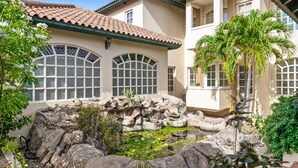 A house with a large arched window, a rock garden, and a palm tree. - Kamay 85 (Noord)