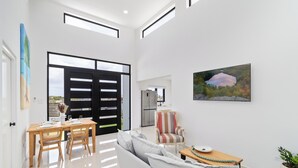 A spacious living area with a sofa, dining table, and chairs. There is a large window with a view of a lake and a painting on the wall. - Tanki Leendert 43-k (Oranjestad)