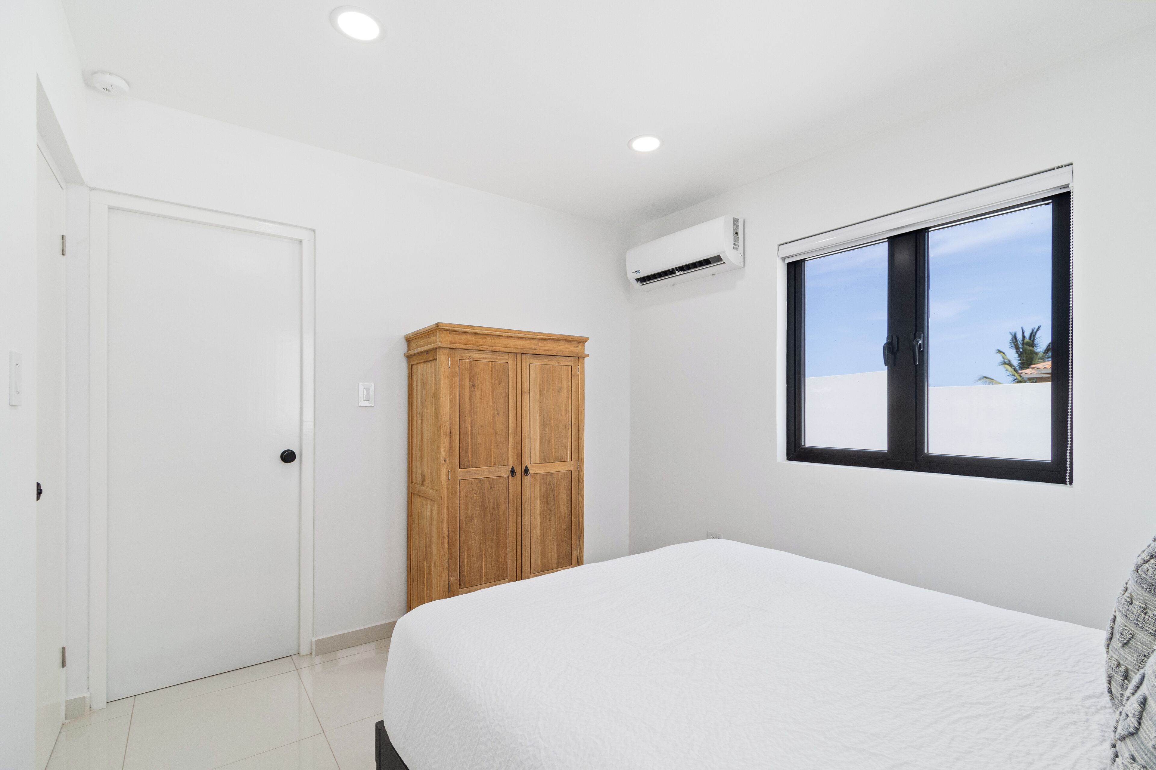Um quarto com cama, guarda-roupa, janela e ar condicionado.