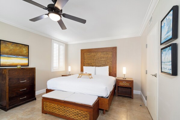 A bedroom with a large bed, a wooden headboard, bedside tables with lamps, a ceiling fan, and artwork on the walls. - Divi Village Condo 6 J.e. Irausquin Blvd 93 (Oranjestad)