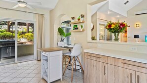 A modern kitchen with a dining area, a ceiling fan, and a view of the outdoors. - Caya Mesa Vista 8 Tierra del Sol (Noord)