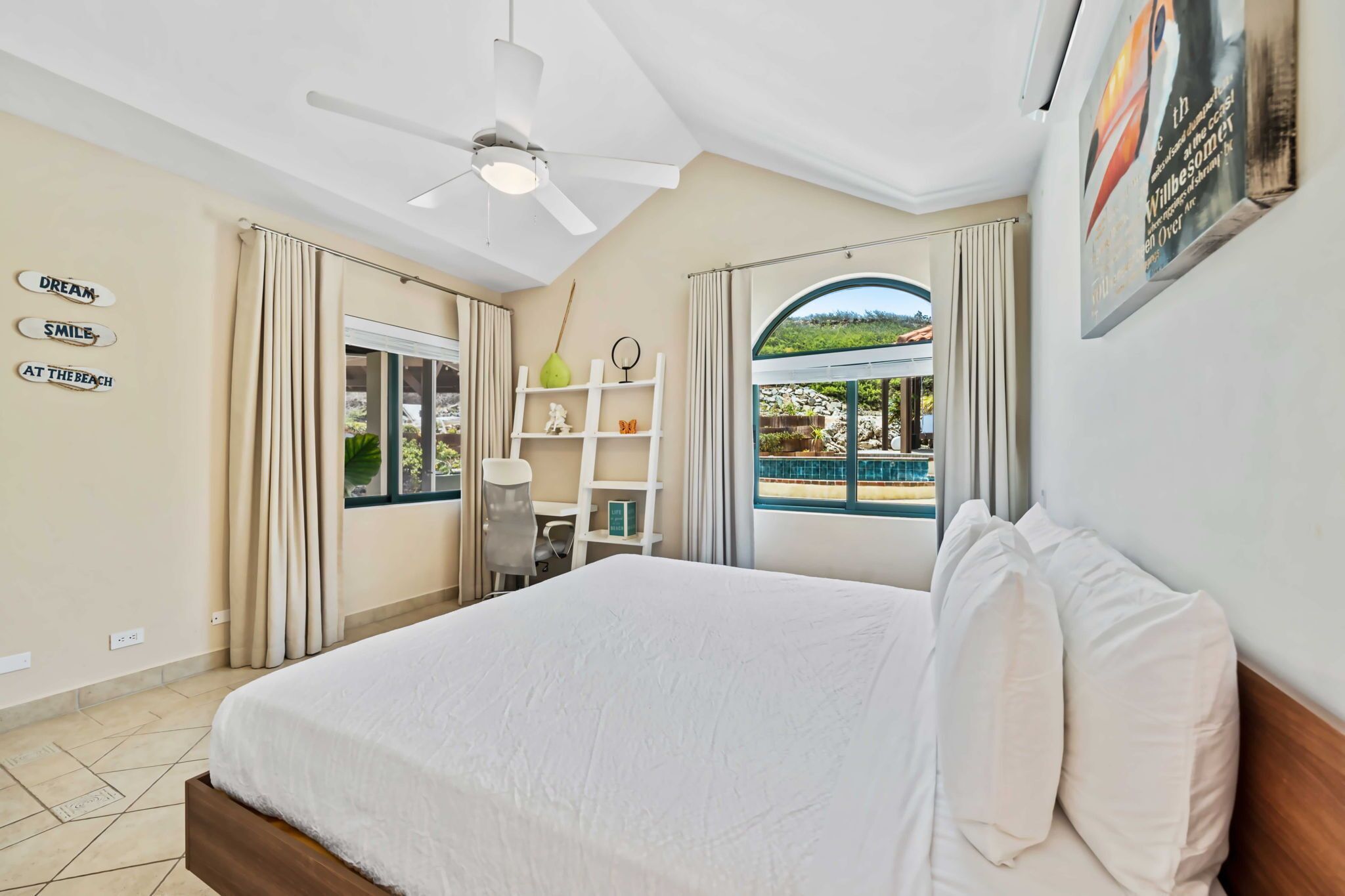 A hotel room with a bed, a desk, and a view of a pool.