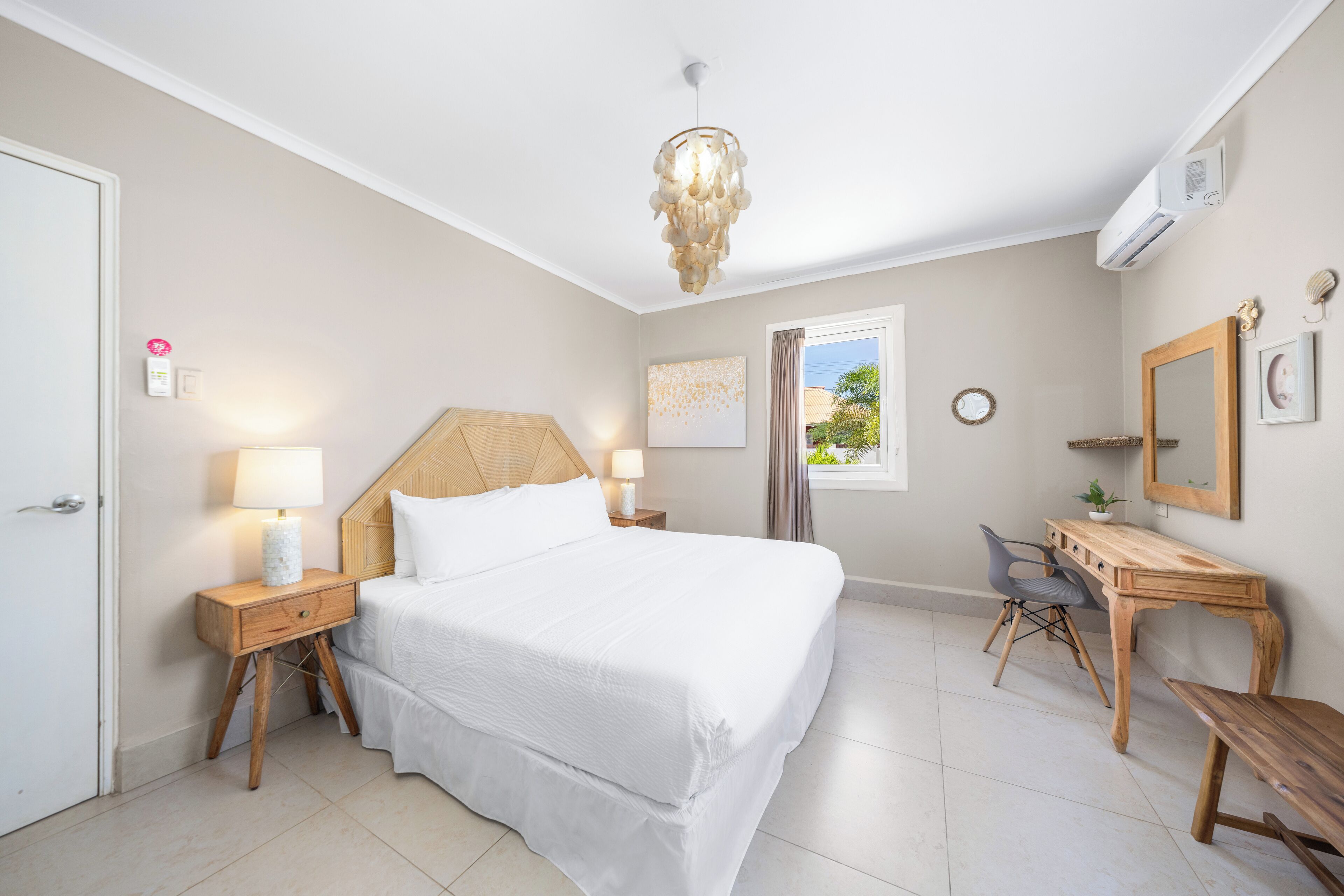 Ein Schlafzimmer mit Bett, Nachttischen, Schreibtisch, Stuhl, Spiegel und Fenster.