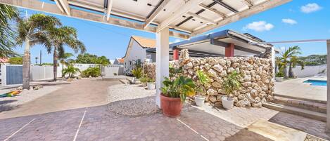 Un espacio al aire libre cubierto con pared de piedra, plantas en macetas y una piscina.