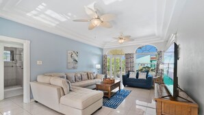 A spacious living room with a sectional sofa, a blue armchair, and a television on a wooden stand. - Washington 41-n (Noord)