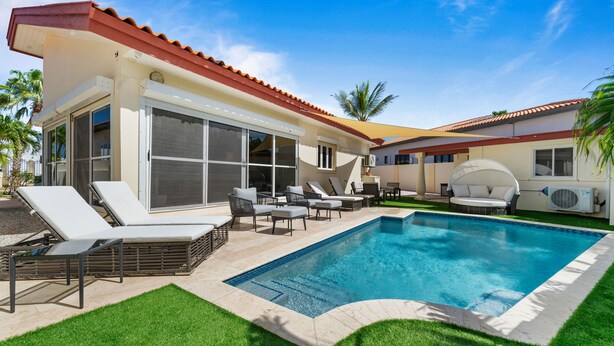 A modern house with a swimming pool, outdoor furniture, and a well-maintained lawn. - Safir 8 (Noord)