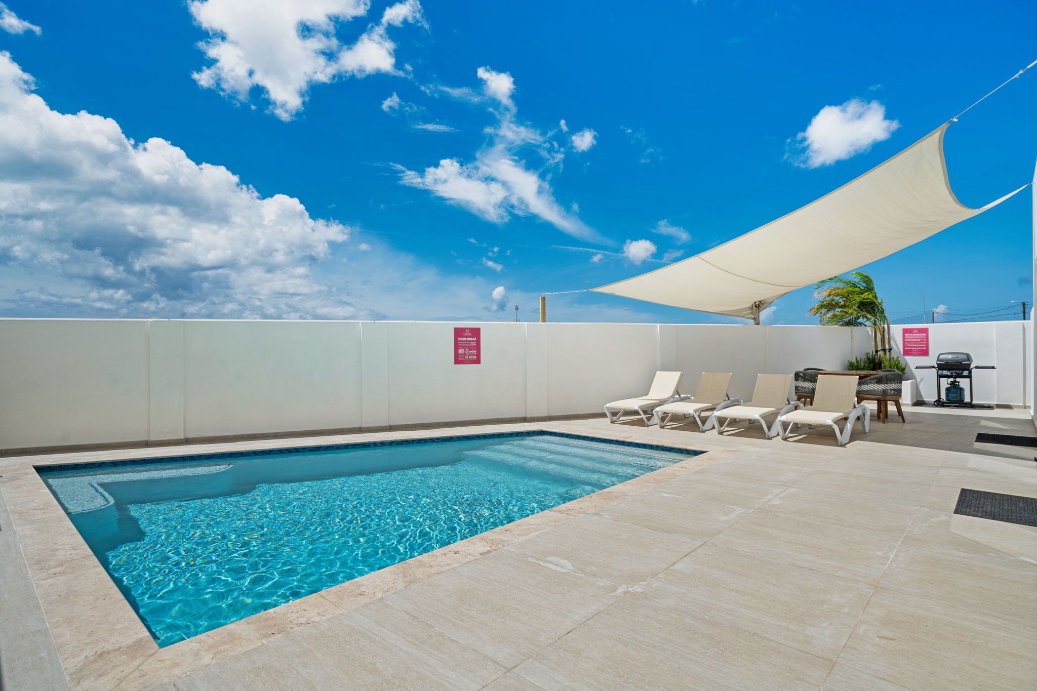 Una piscina con sillas de descanso y una zona sombreada.