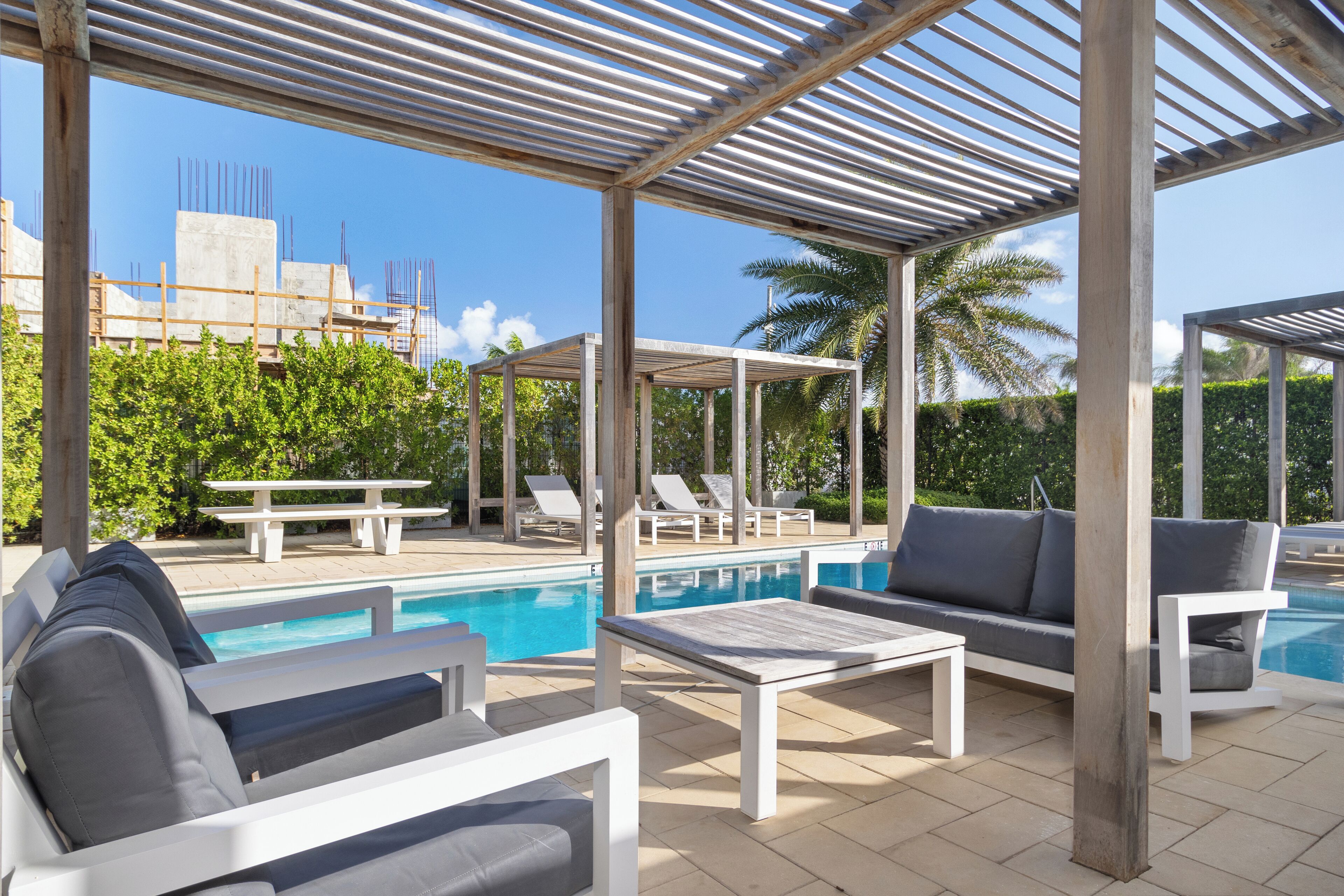 Un espace extérieur abrité comprenant une piscine, des chaises longues et une table.