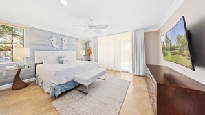 A modern bedroom with a large bed, a ceiling fan, a TV, and a view of palm trees. - Divi Village Condo 33 J.e. Irausquin Blvd 93 (Oranjestad)