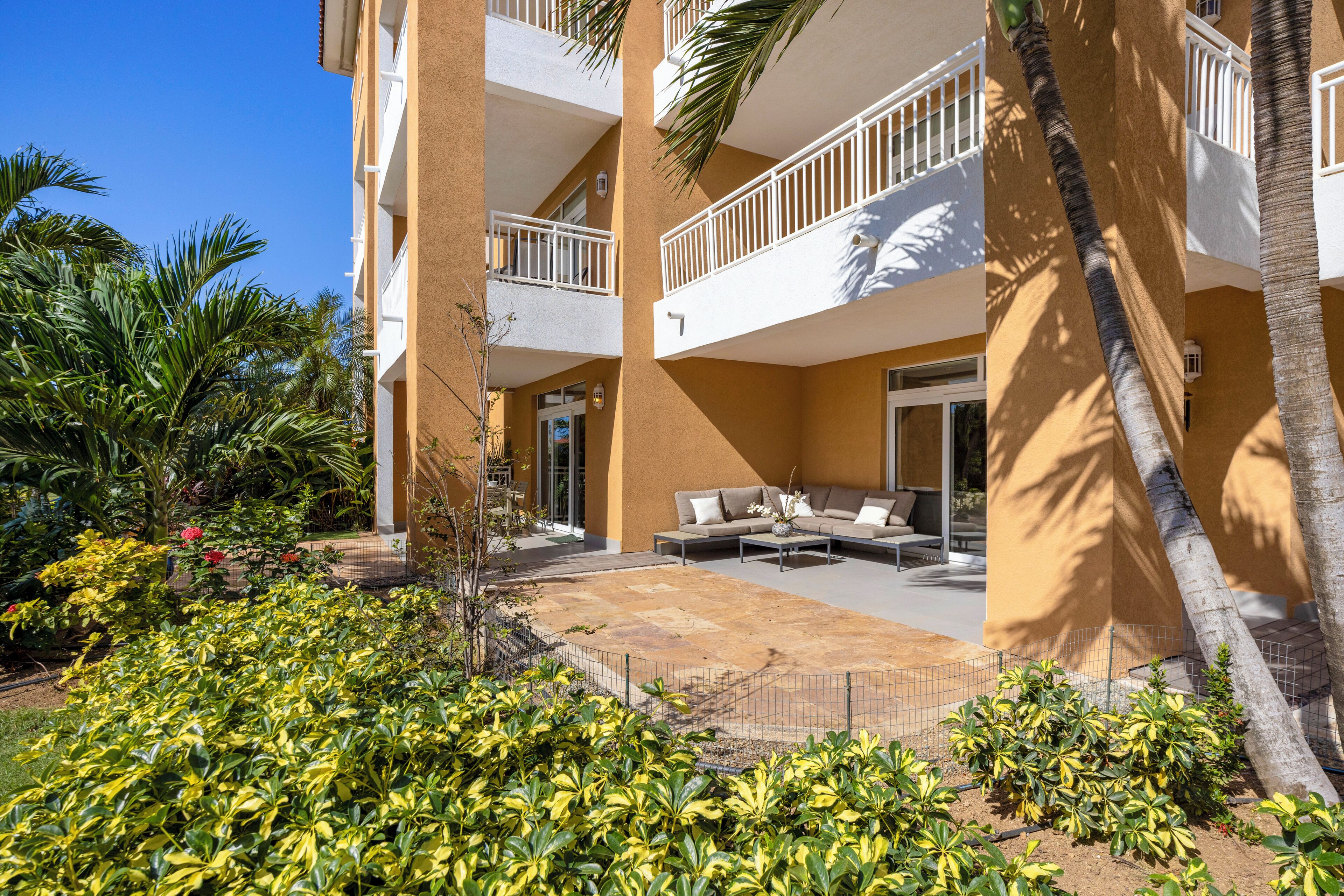 A multi-story hotel with balconies, outdoor seating, and tropical landscaping.