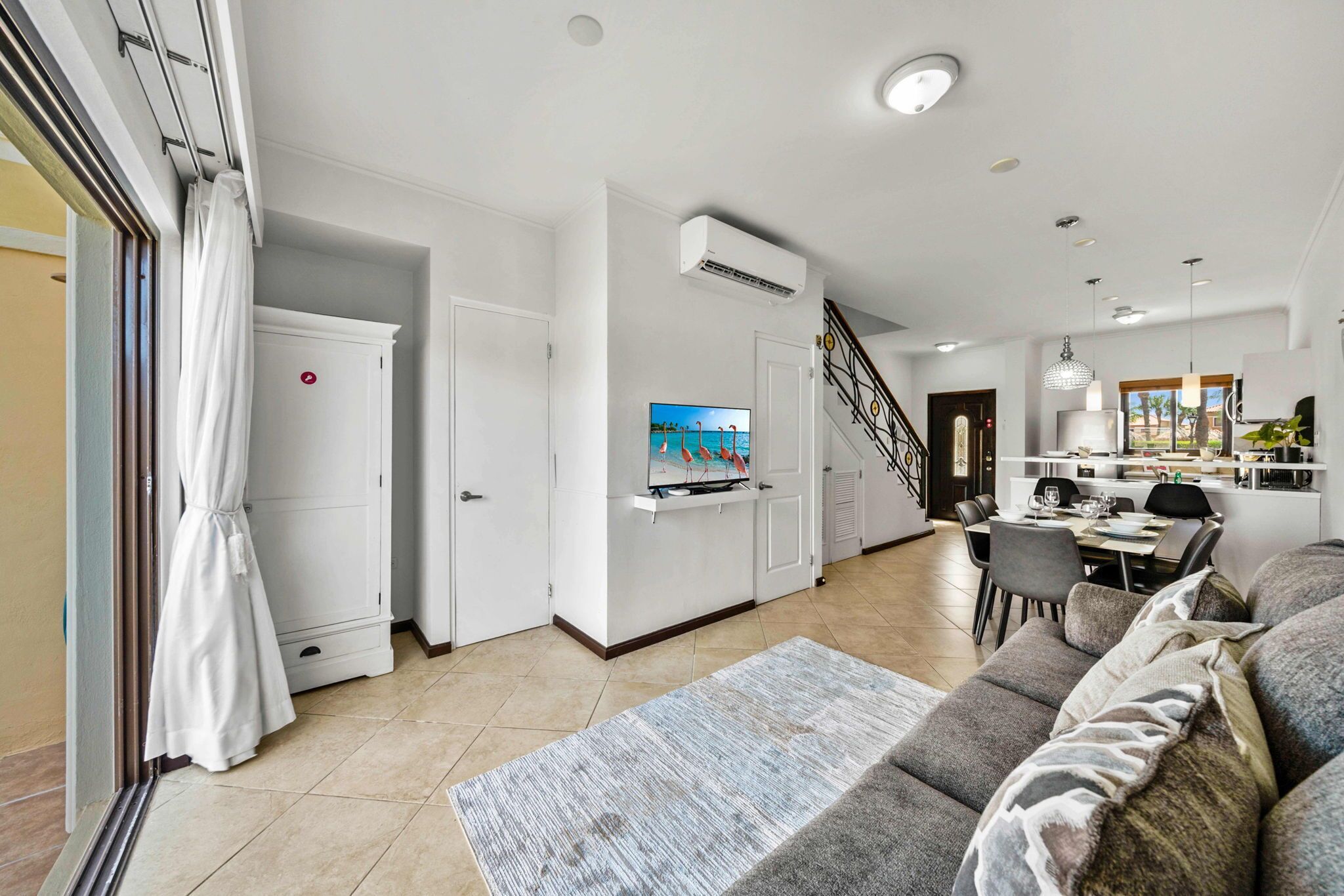 A spacious living area with a sofa, TV, and dining table.